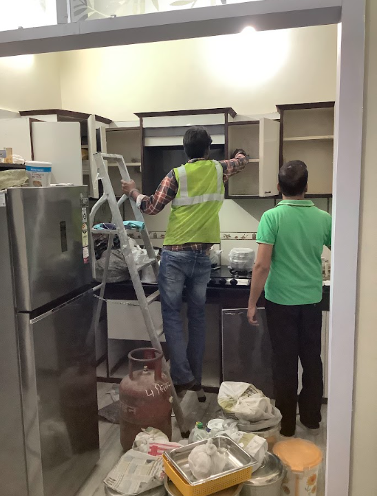 OPC technician performing kitchen cabinet pest control treatment